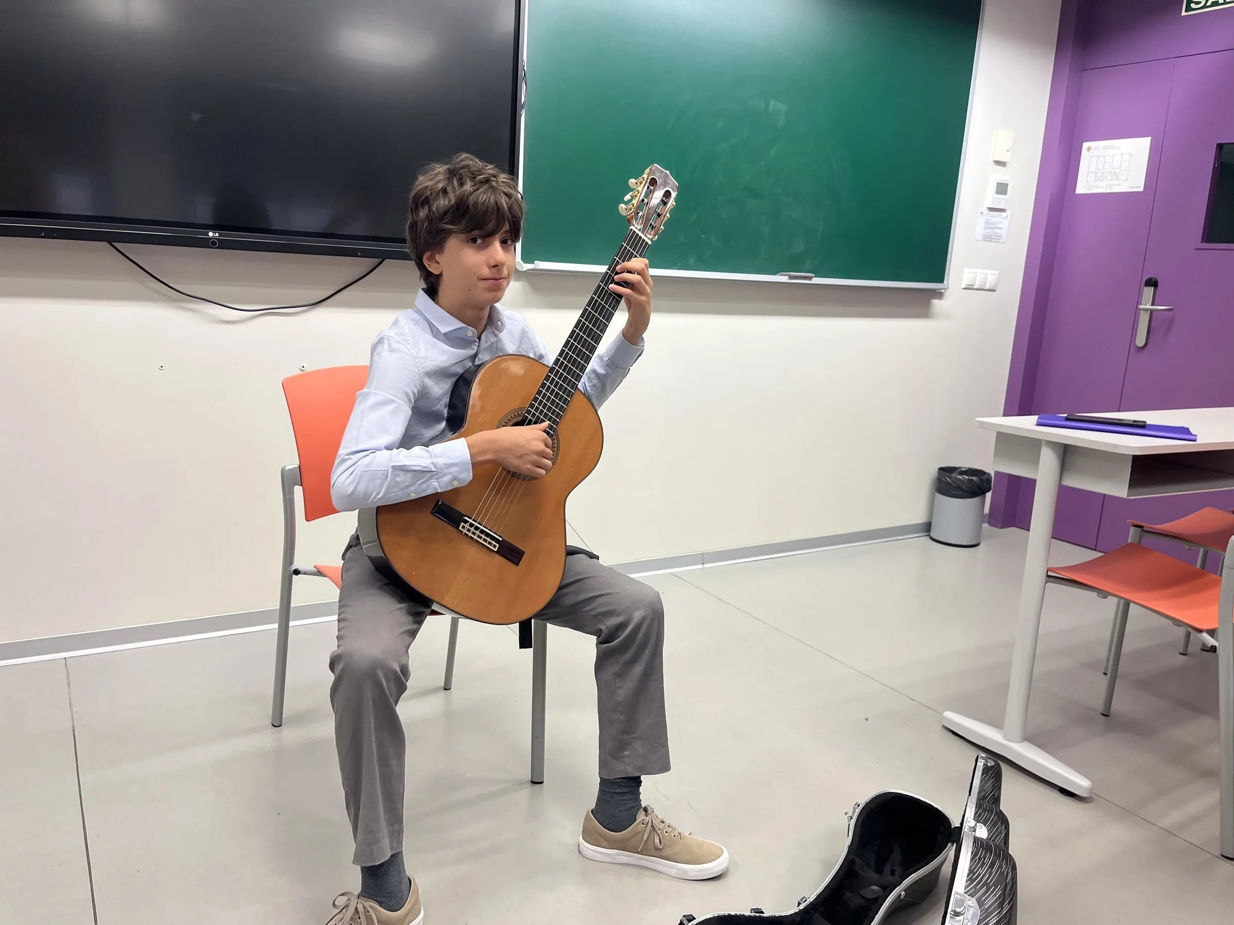Nestor seated with his guitar before a class at Elche.
